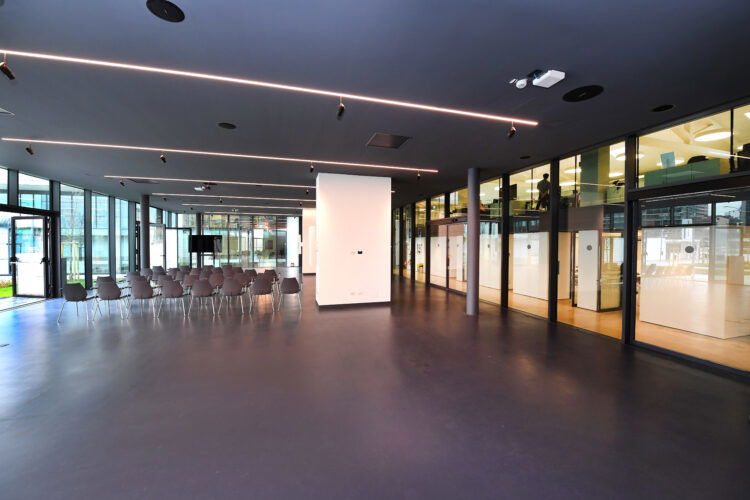 Sala interna con sedute e grandi finestre, illuminazione soffusa e dettagli architettonici moderni.