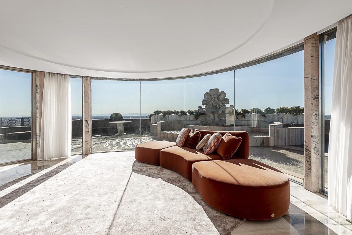 Salotto panoramico con vetrate a 360° e vista su Milano, arredato con divani di design e dettagli di lusso