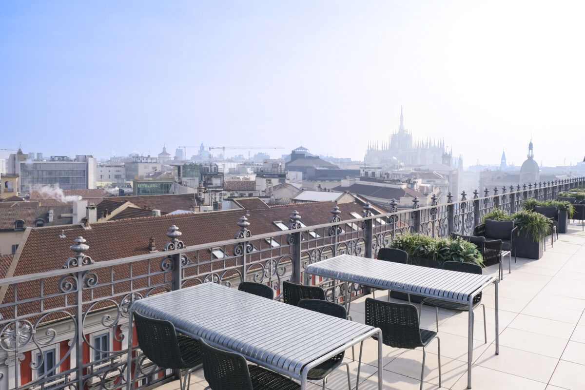 Terrazza con tavoli e sedie affacciata sui tetti di Milano e vista sul Duomo
