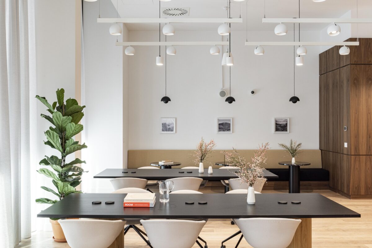 Spazio lounge e coworking con tavoli neri e illuminazione di design.
