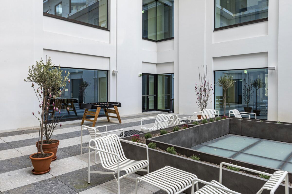 Cortile esterno con sedute bianche e piante in vaso ideale per eventi outdoor a Milano.