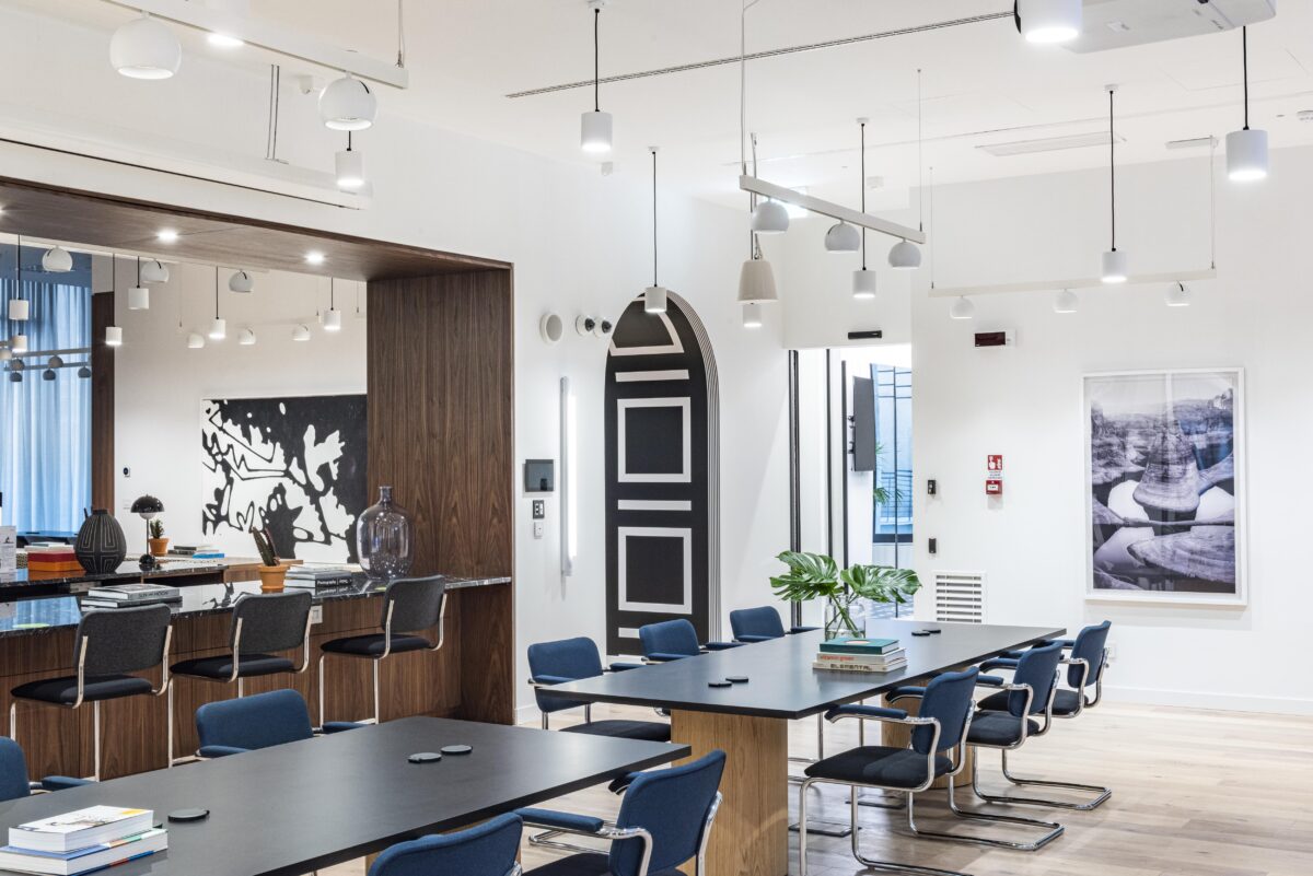Sala riunioni con sedute blu e parete decorativa in legno presso Loft Eventi Mazzini a Milano.