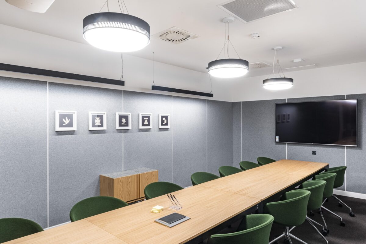 Sala conferenze con tavolo in legno e sedie verdi in stile contemporaneo.